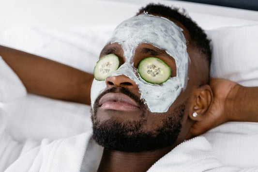 Man relaxing with a hydrating face mask and cucumber slices as part of a skincare routine