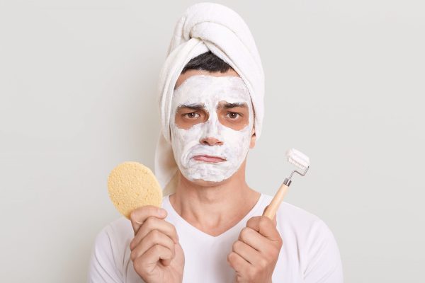 Man wearing a face mask and holding skincare tools, illustrating simple tips for dull and tired-looking skin