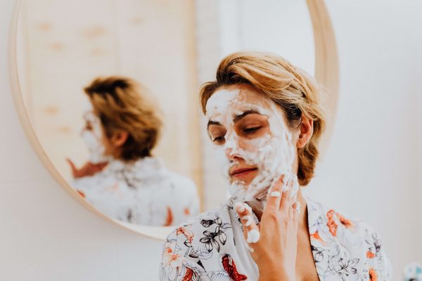 Woman applying a face mask, illustrating skincare tips for smoke-damaged skin