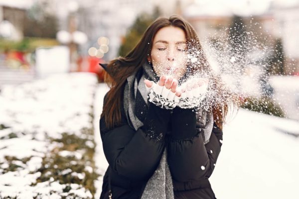 Woman outdoors in snowy weather, illustrating winter skincare tips for healthy glowing skin