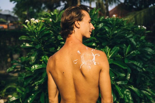 Man outdoors with sunscreen on his back, representing care for sun-damaged skin
