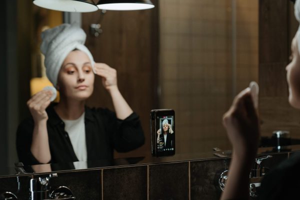 Woman doing her skincare routine in a mirror, illustrating how many skincare products you really need