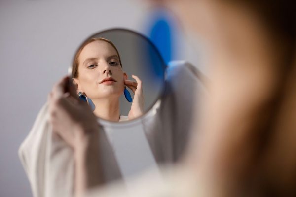 Woman looking in a mirror, representing visible signs of skin aging