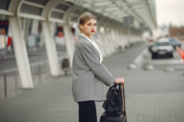 Woman traveling with luggage, representing a skincare routine for healthy skin while traveling