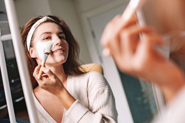 Woman applying a face mask at home, illustrating simple steps for an at-home facial