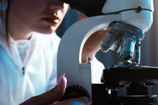 Skincare researcher using a microscope, representing the science and research behind Regene Supreme skincare formulations