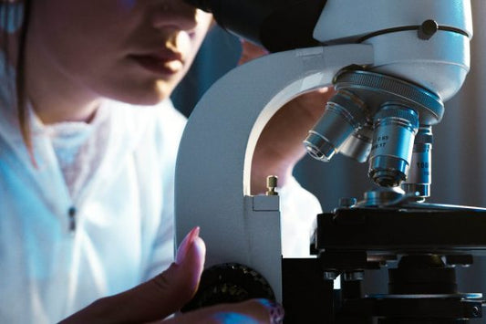 Skincare researcher using a microscope, representing the science and research behind Regene Supreme skincare formulations