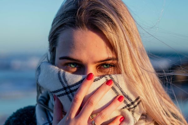 Woman covering her face outdoors, illustrating how anti-pollution skincare helps protect skin from environmental pollution