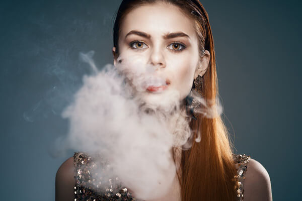 Young woman breathing out smoke